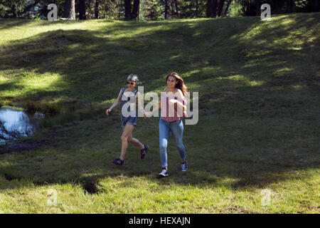 Two female friends running in forest glade, Sattelbergalm, Tyrol, Austria Stock Photo