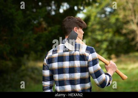 Rear view of man in forest carrying axe on shoulder Stock Photo