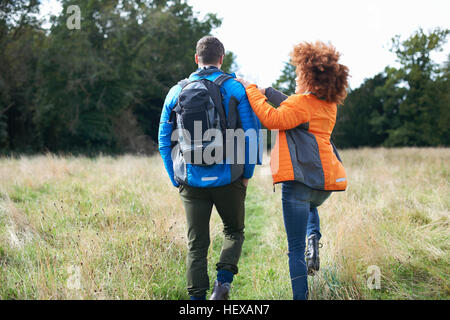 Rear view of couple hiking in field Stock Photo