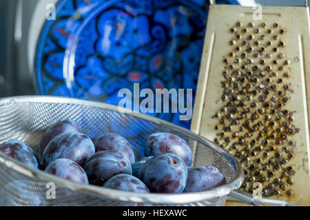 Plums in sieve and grater Stock Photo