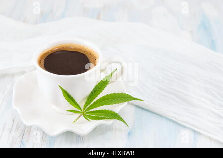 Hot coffee and marijuana leaves on a table Stock Photo
