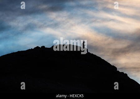 Silhouette of a man on a mountain using a cell phone Stock Photo