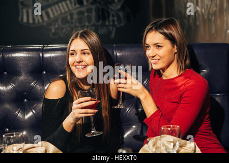 two young beautiful woman relaxing in the restaurant and drinking wine Stock Photo