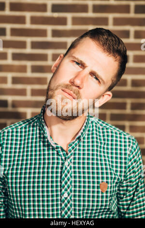 dissatisfied man looking at the camera on Brick wall background Stock Photo