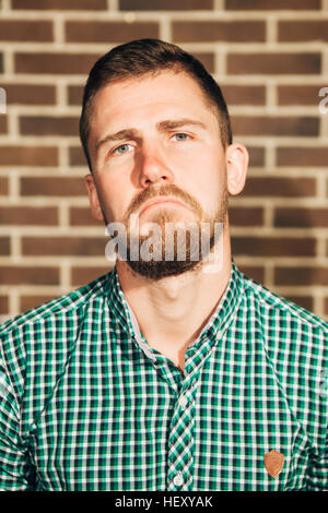 dissatisfied man looking at the camera on Brick wall background Stock Photo