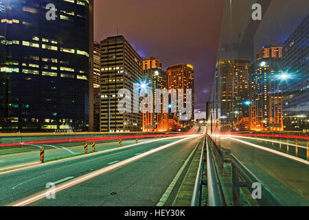 Sydney city CBD towers and skyscrapers around Circular Quay and Cahill Express way with blurred head lights of driving cars. Stock Photo