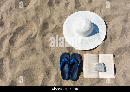 abstract and conceptual summer, holidays at the beach. With a white hat, blue slippers flip-flops and a book with a lid on it. Stock Photo