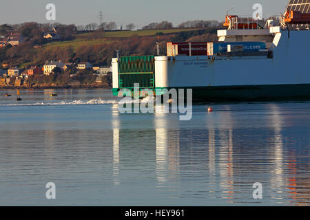 Very large boat  turning to face up stream in calm blue waters with the sun shining and waterside properties in the distance. Stock Photo