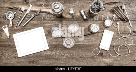 Bar counter with tools, accessories and electronic devices. Drink glasses on wooden table background Stock Photo