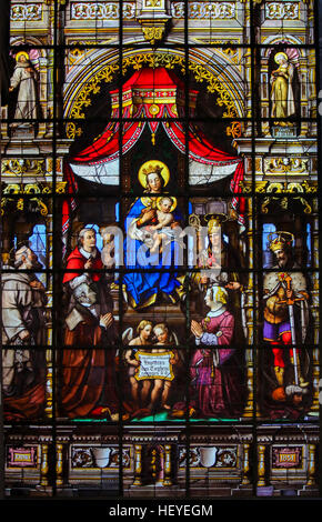 Stained Glass (1851) in Saint Nicholas Church, Ghent, depicting Mother Mary and the Infant Jesus, Madonna and Child, and the donors and various saints Stock Photo