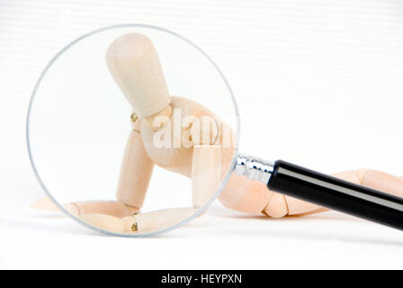 Magnifying glass held over a jointed mannequin: symbol for a transparent person Stock Photo