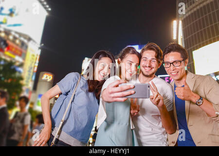 Caucasian couple enjoying sightseeing with Japanese friends in Tokyo, Japan Stock Photo