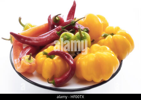Yellow bell peppers with red and yellow chili peppers (Capsicum) on a plate Stock Photo