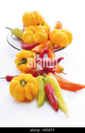 Yellow bell peppers with red and yellow chili peppers (Capsicum) on a plate Stock Photo