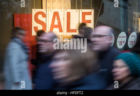 Numerous people walk past a shop window presenting the word 'Sale' in large letters during the first day of business after the Christmas holidays at the shopping mile 'Zeil' in Frankfurt/Main, Germany, 27 December 2016. Photo: Frank Rumpenhorst/dpa Stock Photo