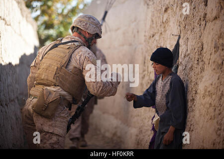 U.S. Marine Lance Cpl. Dominic Evola, a 29-year-old rifleman with Jump Platoon, Headquarters and Service Company, 3rd Battalion, 3rd Marine Regiment, from Medford, N.J., greets an Afghan boy by “pounding fists” while traveling to a local residence for a shura here, Nov. 22. Following their recent assumption of security responsibility in Garmsir, the leadership of “America’s Battalion” joined District Governor Mohammad Fahim to visit and interact with citizens throughout the district, Nov. 22 to 24. During the visits, Fahim and the Marines discussed issues like tribal unity, education, insurgen Stock Photo