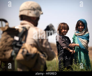 Afghan girls shyly request a bottle of water from U.S. Marine Lance Cpl. Michael Straub, a team leader with 1st Platoon, India Company, 3rd Battalion, 3rd Marine Regiment, and 23-year-old native of Lykens, Pa., as Straub and fellow Marines passed through farmland during a security patrol here, April 30, 2012. On the final patrol of their seven-month deployment, the Marines toured the Durzay region of Helmand province's Garmsir district to disrupt possible insurgent activity. After arriving in Garmsir in October 2011, the Marines aided Afghan National Security Forces in assuming lead security r Stock Photo