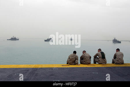 050422-M-5900L-047 Suez Canal (April 22, 2005) - Marines assigned to the 26th Marine Expeditionary Unit (Special Operations Capable) sit at the bow of the amphibious assault ship USS Kearsarge (LHD 3) and watch USS Normandy (CG 60), far left, USS Ponce (LPD 15), middle left, and USS Ashland (LSD 48), far right. Kearsarge and embarked 26th Marine Expeditionary Unit are on a regularly scheduled deployment in support of the Global War on Terrorism. U.S. Marine Corps photo by Lance Cpl. Daniel R. Lowndes (RELEASED) US Navy 050422-M-5900L-047 Marines assigned to the 26th Marine Expeditionary Unit ( Stock Photo