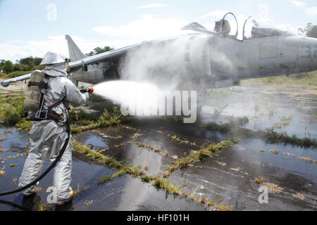 An aircraft rescue firefighter sprays down an AV-8B Harrier with jets of water to put out any last remnants of a fire during a training exercise at Marine Corps Auxiliary Landing Field Bogue, N.C., Sept. 14. The mission of aircraft rescue firefighters is to save lives and property. Sgt. Keith Molinary, the training chief of the Marine Wing Support Squadron 271 aircraft rescue firefighters, said it is useful to train alongside the rest of the squadron to get everyone on the same page. 'Workhorses refresh capabilities with field training 120914-M-AF823-104 Stock Photo