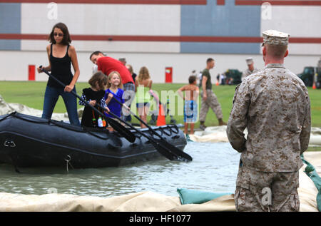 Cpl. John A. L. Silkey, a heavy equipment mechanic with 2nd Maintenance Battalion, 2nd Marine Logistics Group, watches over a group of visitors as they struggle to navigate their zodiac on a man-made pool set up for the battalion’s open house aboard Camp Lejeune, N.C., Sept. 19, 2012. Each of the battalion’s six companies set up stations for families and friends, which allowed them to experience some of the things their Marines do to support operations aboard the base. Marines open doors for families, friends 120919-M-ZB219-090 Stock Photo