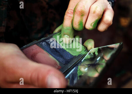 An Infantry Training Battalion student applies camoflauge paint to his face and neck before beginning Patrol Week near Camp Geiger, N.C., on Oct. 28, 2013. Patrol week is a five-day training event that teaches infantry students basic offensive, defensive and patrolling techniques. Delta Company is the first infantry training company to fully integrate female Marines into an entire training cycle. This and future comanies will evaluate the performance of the female Marines as part of ongoing research into opening combat-related job fields to women. (U.S. Marine Corps photo by Sgt. Tyler L. Main Stock Photo