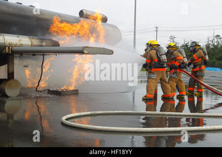 Firefighters battle a fire during a mobile aircraft fire training device exercise at the Camp Hansen Joint Training Facility May 2. Firefighters used the device to create controlled burns in a replicated fuselage. The flames, coupled with smoke machines and audio devices, create realistic training conditions for the firefighters. The firefighters are with Marine Corps Installation Pacific Fire and Emergency Services. (Photo by Lance Cpl. Henry J. Antenor) Firefighters receive unique training opportunity 130502-M-FX659-795 Stock Photo