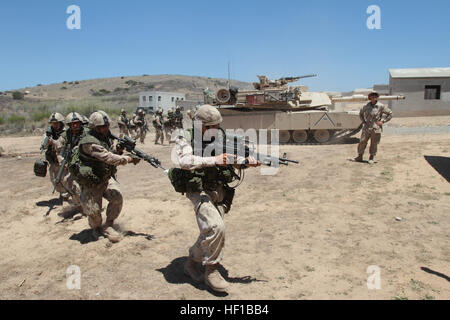 Canadian soldiers serving with 2nd Battalion, Royal 22nd Regiment, move into an urban training course while a M1A1 Abrams tank provides security during Exercise Dawn Blitz here, June 21, 2013. Canadian soldiers coordinated movements with Marines from 1st Tank Battalion to clear the mock village of enemy role players. Dawn Blitz 2013 is a scenario-driven exercise designed to test Navy and Marine Corps forces at the Marine Expeditionary Brigade (MEB) and Expeditionary Strike Group (ESG) level, while promoting military-to-military cooperation and interoperability with partnered nations. Participa Stock Photo