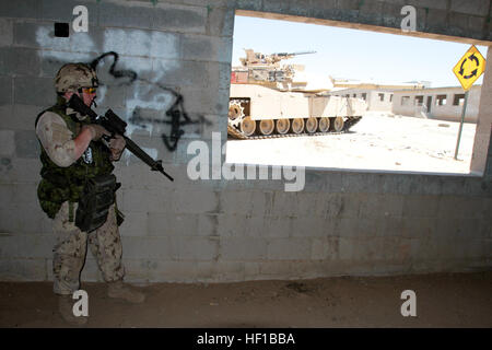 Canadian Army Sapper Alexander Boucher, a section member serving with 2nd Battalion, Royal 22nd Regiment, takes cover inside a building while a M1A1 Abrams Tank provides cover during Exercise Dawn Blitz here, June 21, 2013. Canadian soldiers coordinated movements with Marines from 1st Tank Battalion to clear the mock village of enemy role players. Dawn Blitz 2013 is a multinational amphibious exercise off the Southern California coast that refocuses Navy and Marine Corps and coalition forces in their ability to conduct complex amphibious operations essential for global crisis response across t Stock Photo