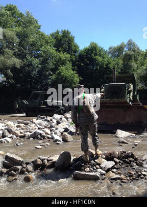 New York Army National Guard engineers with Task Force Engineer, a mixed force comprised of U.S. Soldiers with the 204th Engineer Battalion, the 206th Military Police Company and the 1427th Transportation Company, assist with debris removal and widening the Otsquago Creek in Fort Plain, N.Y., July 5, 2013, in support of the National Guard's flash flooding recovery efforts in the Mohawk Valley. (U.S. Army National Guard photo by Lt. Col. Christopher Panzer/Released) Mohawk Valley flood relief 130705-Z-ZZ999-007 Stock Photo