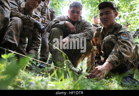 Sgt. Ts. Galmunkh, a member of the 065 Communication Unit, Mongolian Armed Forces, sets a trap while being observed by Cpl. Justin Haish, an instructor for the Khaan Quest 2013 survival course and assigned to the Jungle Warfare Training Center in Camp Gonsalves, Okinawa, Japan, Aug. 7. Khaan Quest is a peacekeeping operations-focused, combined training event between U.S. Marine Corps Forces Pacific, U.S. Army Pacific, and the MAF. MARFORPAC and USARPAC have conducted similar training with MAF since 2003, and this exercise marks the 11th iteration of Khaan Quest. Military personnel from Austral Stock Photo