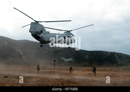 MARINE CORPS BASE CAMP PENDLETON, Calif. – Marines with Kilo Company, 3rd Battalion, 5th Marine Regiment, fast rope from a CH-46 Sea Knight helicopter and secure an objective area during a training exercise here, Oct. 9, 2013. When fast roping, Marines deploy a heavy rope from the rear and center of the helicopter and use their arms and legs to control their descent. Once on the ground, Marines swiftly spread out and secure the area until all Marines unload. Fast roping enables a company of Marines to quickly insert into hostile or inaccessible terrain. Fast roping prepares Marines for rapid s Stock Photo