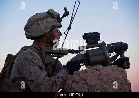 Lance Cpl. Nathan Gulbronson, a Lambertville, Mich., native and rifleman with 1st Battalion, 9th Marines, watches for insurgent activity from behind a compound wall during a firefight with insurgents near the Bari Gul Bazaar, Nad Ali District, Helmand province, Afghanistan, Dec. 4, 2013. Gulbronson used his M32 grenade launcher to provide cover for Marines clearing a nearby compound. Under Fire 131204-M-ZB219-046 Stock Photo