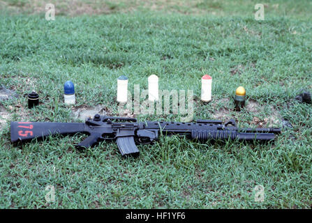 An M16A2 rifle equipped with an M203 grenade launcher lies in the grass near some of the types of 40 mm ammunition available for use with the M203.  The cartidges are, from left to right, multiple projectile, practice, green star flare, white star flare, red star flare and high explosive. M16 M203 40mm ammunition Stock Photo