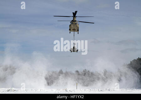 An M-177 155mm howitzer is transported by a CH-47 Chinook during cold weather sling load operations at Camp Grayling Joint Maneuver Training Center, Mich., Feb 28, 2014. (Michigan National Guard photo by Staff Sgt. Kimberly Bratic/Released) Michigan National Guard conducts cold weather sling load and howitzer live fire exercise 140228-Z-LE308-007 Stock Photo