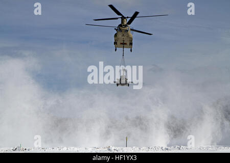 An M-177 155mm howitzer is transported by a CH-47 Chinook during cold weather sling load operations at Camp Grayling Joint Maneuver Training Center, Mich., Feb 28, 2014. (Michigan National Guard photo by Staff Sgt. Kimberly Bratic/Released) Michigan National Guard conducts cold weather sling load and howitzer live fire exercise 140228-Z-LE308-006 Stock Photo