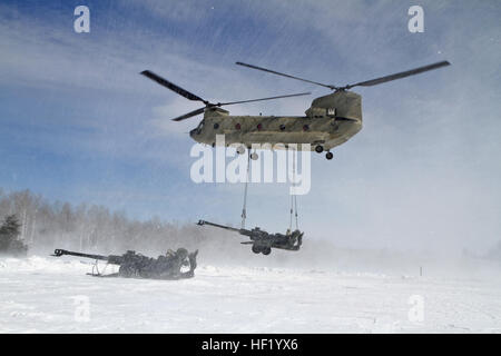 An M-177 155mm howitzer is transported by a CH-47 Chinook during cold weather sling load operations at Camp Grayling Joint Manuever Training Center, Mich., Feb 28, 2014. (Michigan National Guard photo by Staff Sgt. Kimberly Bratic/Released) Michigan National Guard conducts cold weather sling load and howitzer live fire exercise 140228-Z-LE308-004 Stock Photo