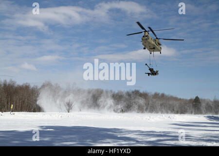 An M-177 155mm howitzer is transported by a CH-47 Chinook during cold weather sling load operations at Camp Grayling Joint Maneuver Training Center, Mich., Feb 28, 2014. (Michigan National Guard photo by Staff Sgt. Kimberly Bratic/Released) Michigan National Guard conducts cold weather sling load and howitzer live fire exercise 140228-Z-LE308-010 Stock Photo