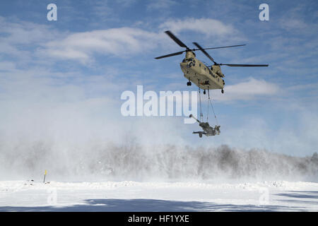 An M-177 155mm howitzer is transported by a CH-47 Chinook during cold weather sling load operations at Camp Grayling Joint Maneuver Training Center, Mich., Feb 28, 2014. (Michigan National Guard photo by Staff Sgt. Kimberly Bratic/Released) Michigan National Guard conducts cold weather sling load and howitzer live fire exercise 140228-Z-LE308-009 Stock Photo