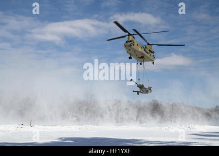 An M-177 155mm howitzer is transported by a CH-47 Chinook during cold weather sling load operations at Camp Grayling Joint Maneuver Training Center, Mich., Feb 28, 2014. (Michigan National Guard photo by Staff Sgt. Kimberly Bratic/Released) Michigan National Guard conducts cold weather sling load and howitzer live fire exercise 140228-Z-LE308-011 Stock Photo