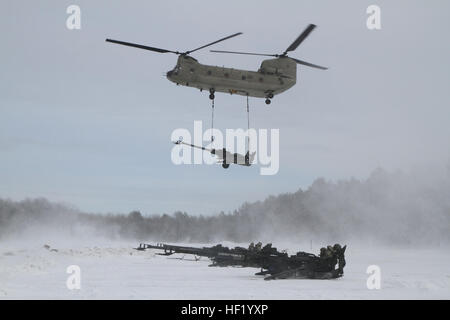 An M-177 155mm howitzer is transported by a CH-47 Chinook during cold weather sling load operations at Camp Grayling Joint Maneuver Training Center, Mich., Feb. 28, 2014. (Michigan National Guard photo by Staff Sgt. Kimberly Bratic/Released) Michigan National Guard conducts cold weather sling load and howitzer live fire exercise 140228-Z-LE308-015 Stock Photo