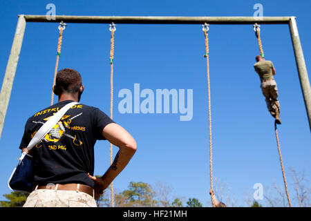 An instructor with 2nd Marine Logistics Group's Corporal's Course observes as a student climbs the rope portion of the obstacle course at Camp Lejeune, N.C., March 20, 2014. The course's instructor cadre is composed of sergeants hand selected to help foster the history, traditions, and operational knowledge essential to Marine Corps leadership in the next generation of noncommissioned officers. CorporalE28099s Course forges next generation of Marine NCOs 140320-M-ZB219-002 Stock Photo