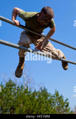 A Marine attending 2nd Marine Logistics Group's Corporal's Course climbs over a bar while completing an obstacle course challenge at Camp Lejeune, N.C., March 20, 2014. Instructors at the course paired hands-on physical training with daily classroom instruction to challenge their students throughout the course. CorporalE28099s Course forges next generation of Marine NCOs 140320-M-ZB219-014 Stock Photo