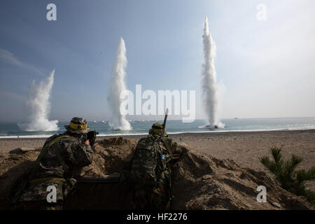 Republic of Korea Marines with 7th Marine Regiment, simulated opposition forces, observe water explosions as Assault Amphibious Vehicles approach shore during Integrated Amphibious Assault Ssang Yong 14 at Doksu-ri Beach, Pohang, South Korea, March 31, 2014. Exercise Ssang Yong is conducted annually in the Republic of Korea (ROK) to enhance interoperability between U.S. and ROK forces by performing a full spectrum of amphibious operations while showcasing sea-based power projection in the Pacific. (U.S. Marine Corps Photo by Cpl. Sara A. Medina, III MEF Combat Camera/Released) ROK, US Marines  Stock Photo