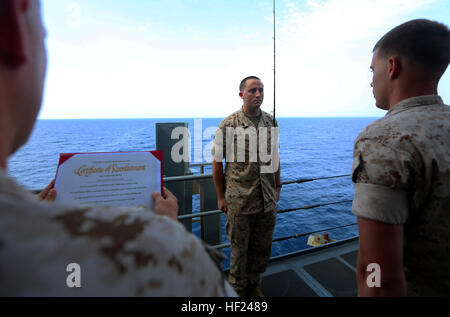 U.S. Marine Corps Sgt. Joshua Lamb, Battalion Landing Team 1st Battalion, 6th Marine Regiment, 22nd Marine Expeditionary Unit (MEU), motor transportation maintenance chief and native of Brick, N.J., stands at attention during his re-enlistment ceremony while fishing aboard the USS Bataan (LHD 5). The 22nd MEU is deployed with the Bataan Amphibious Ready Group as a theater reserve and crisis response force throughout U.S. Central Command and the U.S. 5th Fleet area of responsibility. (U.S. Marine Corps photo by Cpl. Caleb McDonald/Released) 22nd MEU Marine re-enlists while fishing at sea 140504 Stock Photo