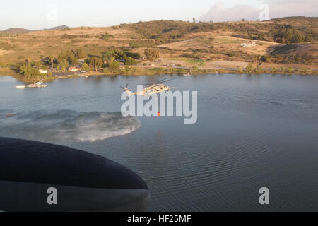 A U.S. Marine Corps CH-53E Super Stallion, Marine Heavy Helicopter Squadron 462 (HMH-462), Marine Air Group 16, 3rd Marine Aircraft Wing (MAW) collect water in bambi buckets during aerial firefighting efforts, May 14, 2014. 3rd MAW aircraft partnered with the California Department of Forestry and Fire Protection to conduct aerial firefighting against several wildfires ablaze in San Diego County. (U.S. Marine Corps photo by Staff Sgt. Carl Atherton 3d MAW COMCAM/RELEASED) California Wild Fires 2014 140514-M-OF641-171 Stock Photo