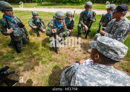 New Jersey Army National Guard drill instructors Staff Sgt. David R. Crenshaw, bottom right, and Sgt. 1st Class Harry R. Martinez, right, explain to members of the Albanian Officer Candidate Class 001 the process of regrouping during improvised explosive device training at Joint Base McGuire-Dix-Lakehurst, N.J., June 4, 2014. Albania is the first State Partnership Program country to send its officer candidates to the United States to attend an Officer Candidate School (OCS) program. The 12-week NJARNG OCS program is modeled after the active-duty program at Fort Benning, Ga., and includes class Stock Photo