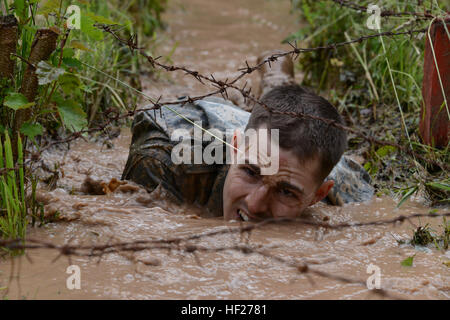 Sgt. James Day, paratrooper assigned to Company B, 1st Battalion, 503rd Infantry Regiment, 173rd Airborne Brigade, crawls through a muddy water-filled trench under barbed wire during the Iron Wolf Best Squad competition, an annual event hosted by the Iron Wolf Mechanized Infantry Brigade, in Rukla, Lithuania, June 5, 2014. The 'Sky Soldiers' of the 173rd are in Lithuania conducting exercises designed to increase NATO interoperability between Lithuanian and American forces. (U.S. Army photo by Staff Sgt. Kimberly Bratic, Michigan National Guard/Released) 173rd Airborne Brigade participates in I Stock Photo