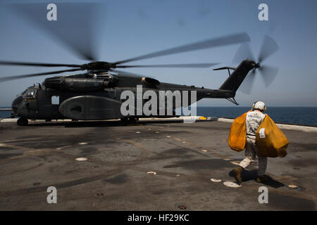 A U.S. Marine with amphibious transport dock ship USS Mesa Verde (LPD 19) combat cargo prepares to load bags of mail onto an MH-53E Sea Dragon with Helicopter Mine Countermeasures Squadron 15 (HM 15). The 22nd Marine Expeditionary Unit is deployed with the Bataan Amphibious Ready Group as a theater reserve and crisis response force throughout U.S. Central Command and the U.S. 5th Fleet area of responsibility. (U.S. Marine Corps photo by Cpl. Manuel A. Estrada/Released) Marines, Sailors depart Mesa Verde with mail, personnel 140703-M-MX805-163 Stock Photo