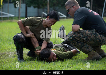 Police Officer 2nd Class Roslene Ramos, from the Philippine National Police, conducts a Mechanical Advantage Control Hold (MACH) after being sprayed with Oleoresin Capsicum (OC), August 8, as part of OC spray training, during Non-Lethal Weapons Executive Seminar (NOLES) 2014. NOLES is an annual field-training exercise and leadership seminar sponsored by U.S. Marine Corps Forces Pacific, and hosted by various nations throughout the Asia-Pacific. This is the 13th iteration of NOLES with members from the AFP, and Philippine National Police participating. (U.S. Marine Corps photo by Cpl. Erik Estr Stock Photo