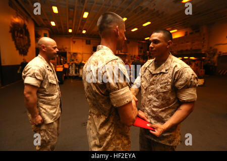 U.S. Marine Corps Cpl. Sergio Aguirrevalle, right, Battalion Landing Team 1st Battalion, 6th Marine Regiment, 22nd Marine Expeditionary Unit (MEU), tank gunner and native of Silver Springs, Md., receives his promotion warrant during a ceremony aboard the amphibious assault ship USS Bataan (LHD 5). The 22nd MEU is deployed with the Bataan Amphibious Ready Group as a theater reserve and crisis response force throughout U.S. Central Command and the U.S. 5th Fleet area of responsibility. (U.S. Marine Corps photo by Gunnery Sgt. Freddy G. Cantu/Released) 22nd MEU Marines promoted aboard Bataan 1409 Stock Photo